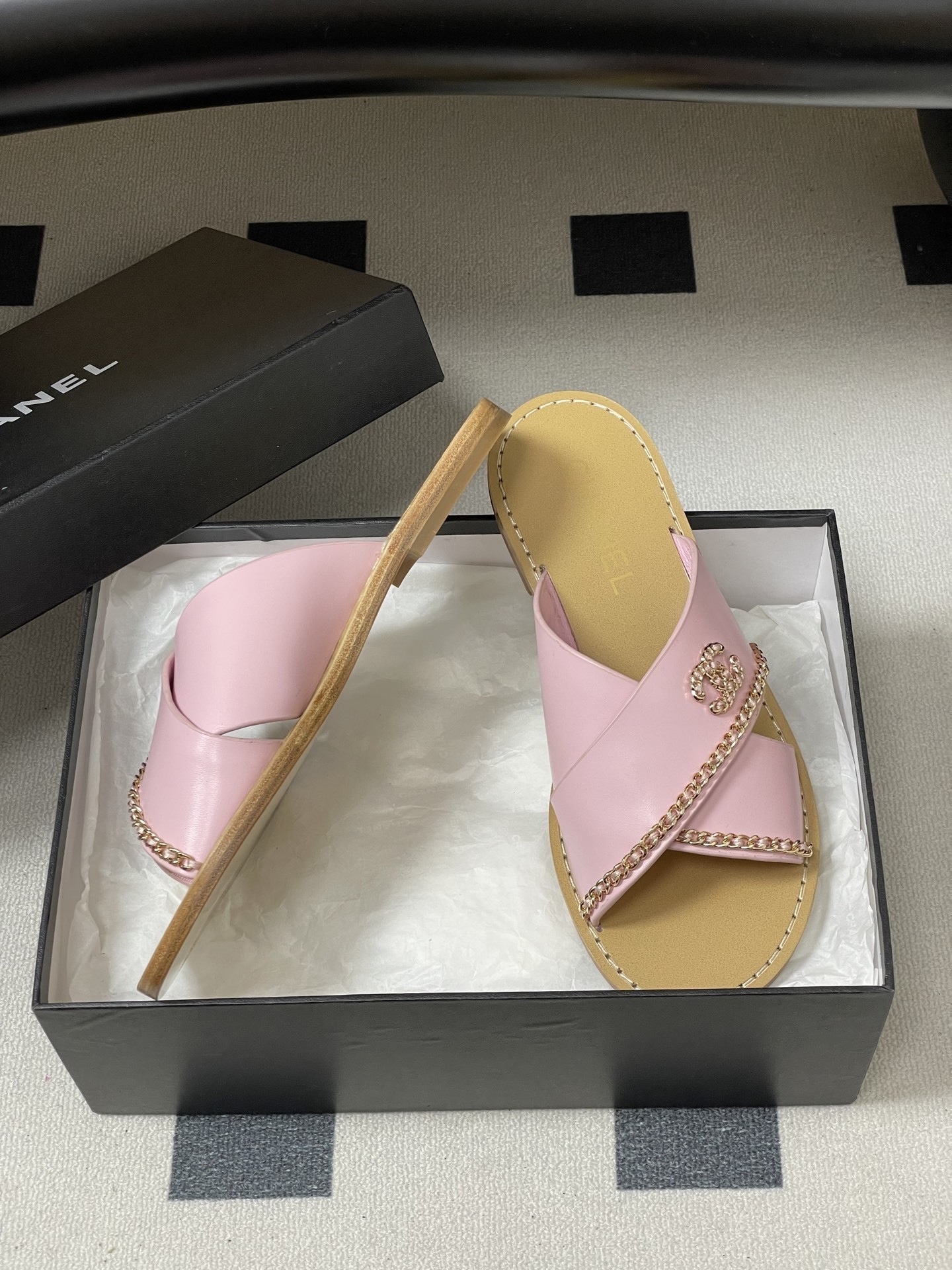 Pair of Chanel light pink leather criss-cross sandals with gold chain detail and CC logo on a black surface - Hình 6