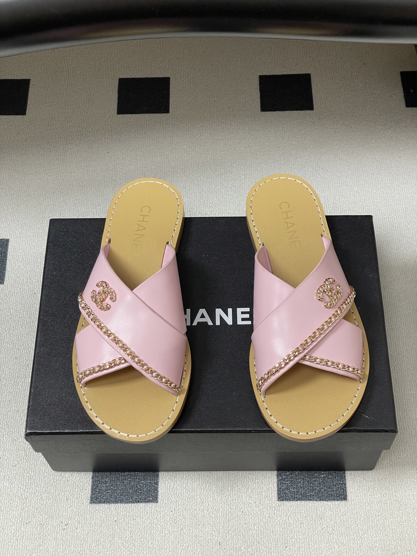 Pair of Chanel light pink leather criss-cross sandals with gold chain detail and CC logo on a black surface - Hình 5