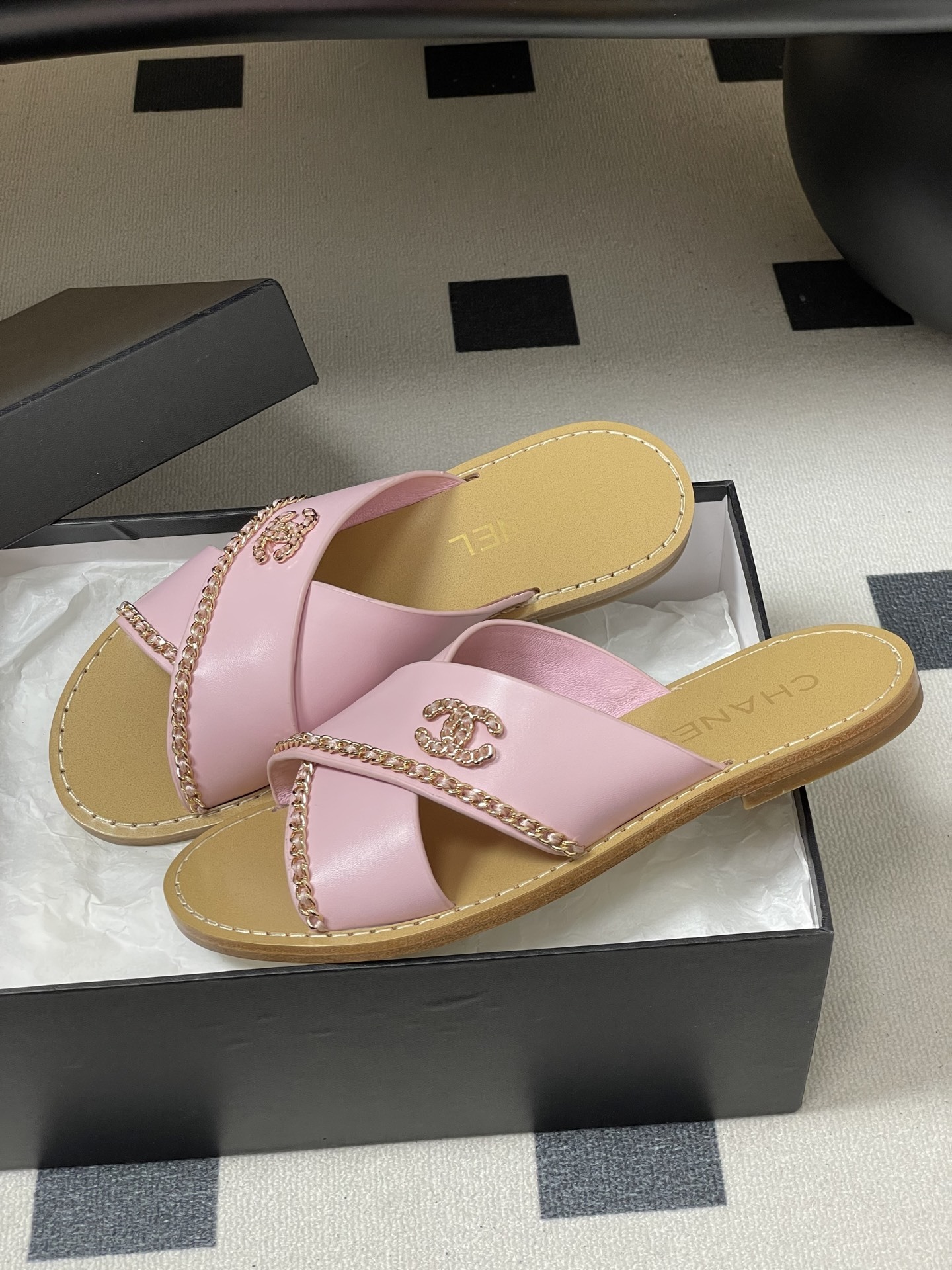 Pair of Chanel light pink leather criss-cross sandals with gold chain detail and CC logo on a black surface - Hình 4