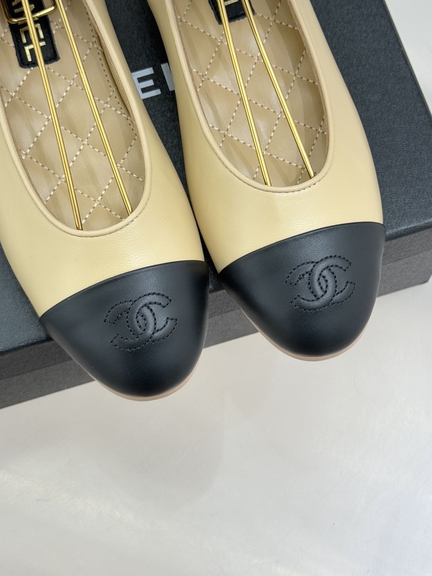 Pair of beige and black leather ballet flats with black silk ribbons on a black box next to a white tweed jacket and quilted bag - Hình 7