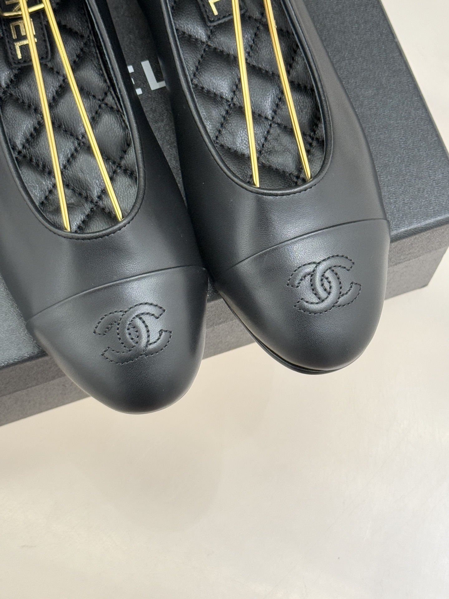 Elegant black leather ballet flats with CC logo on toe and black silk scarf ankle ribbons displayed on a black box - Hình 7