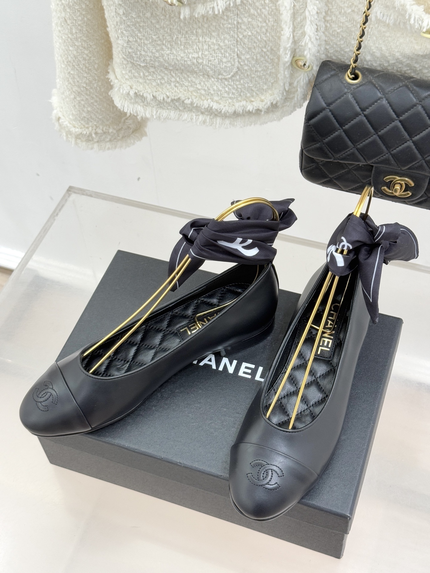 Elegant black leather ballet flats with CC logo on toe and black silk scarf ankle ribbons displayed on a black box - Hình 2