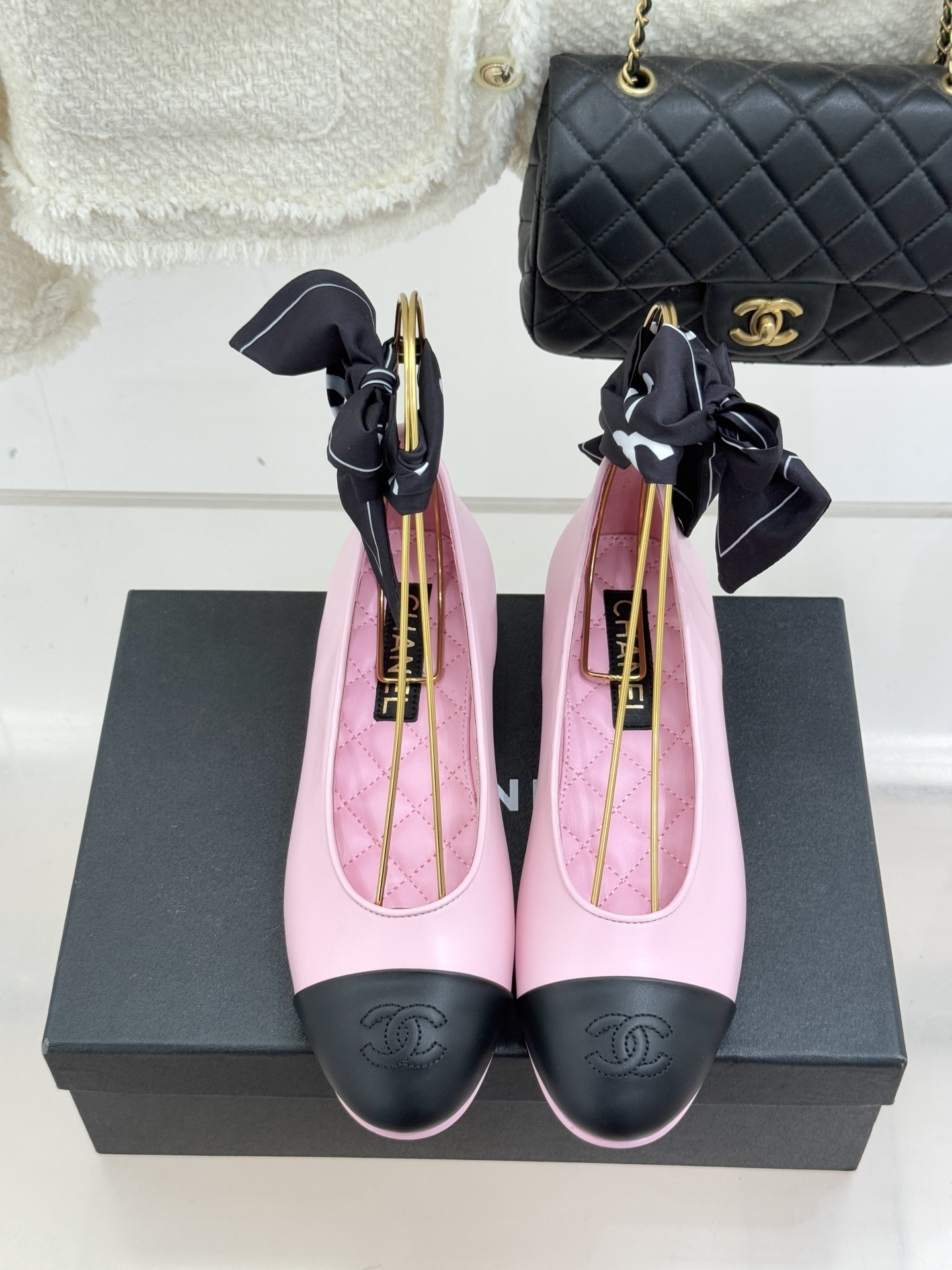 Luxury Chanel pink leather ballet flats with black toe caps and embossed logo on a branded box. - Hình 4
