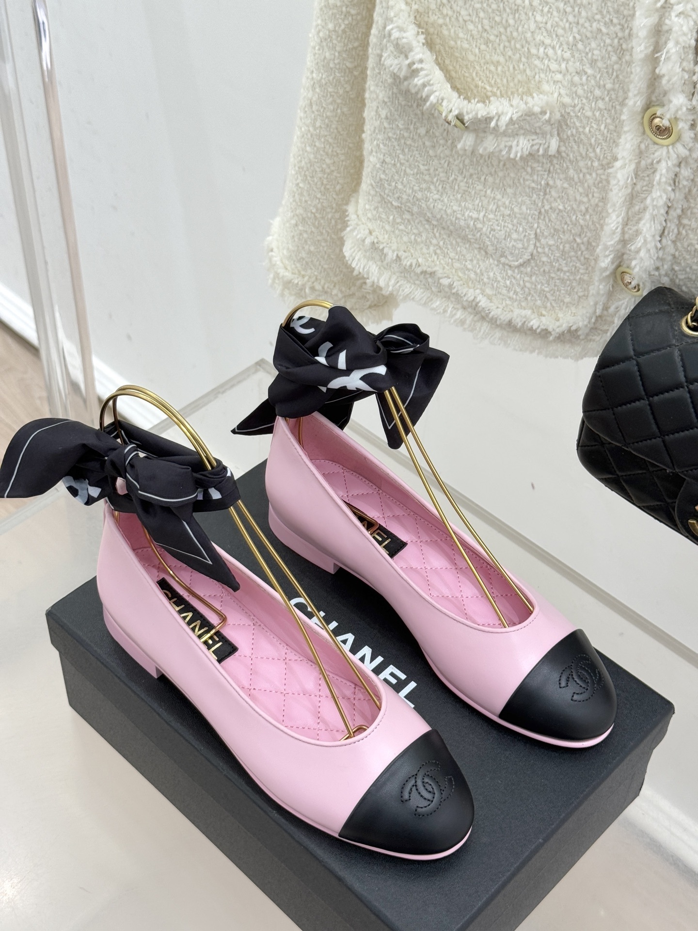 Luxury Chanel pink leather ballet flats with black toe caps and embossed logo on a branded box. - Hình 3