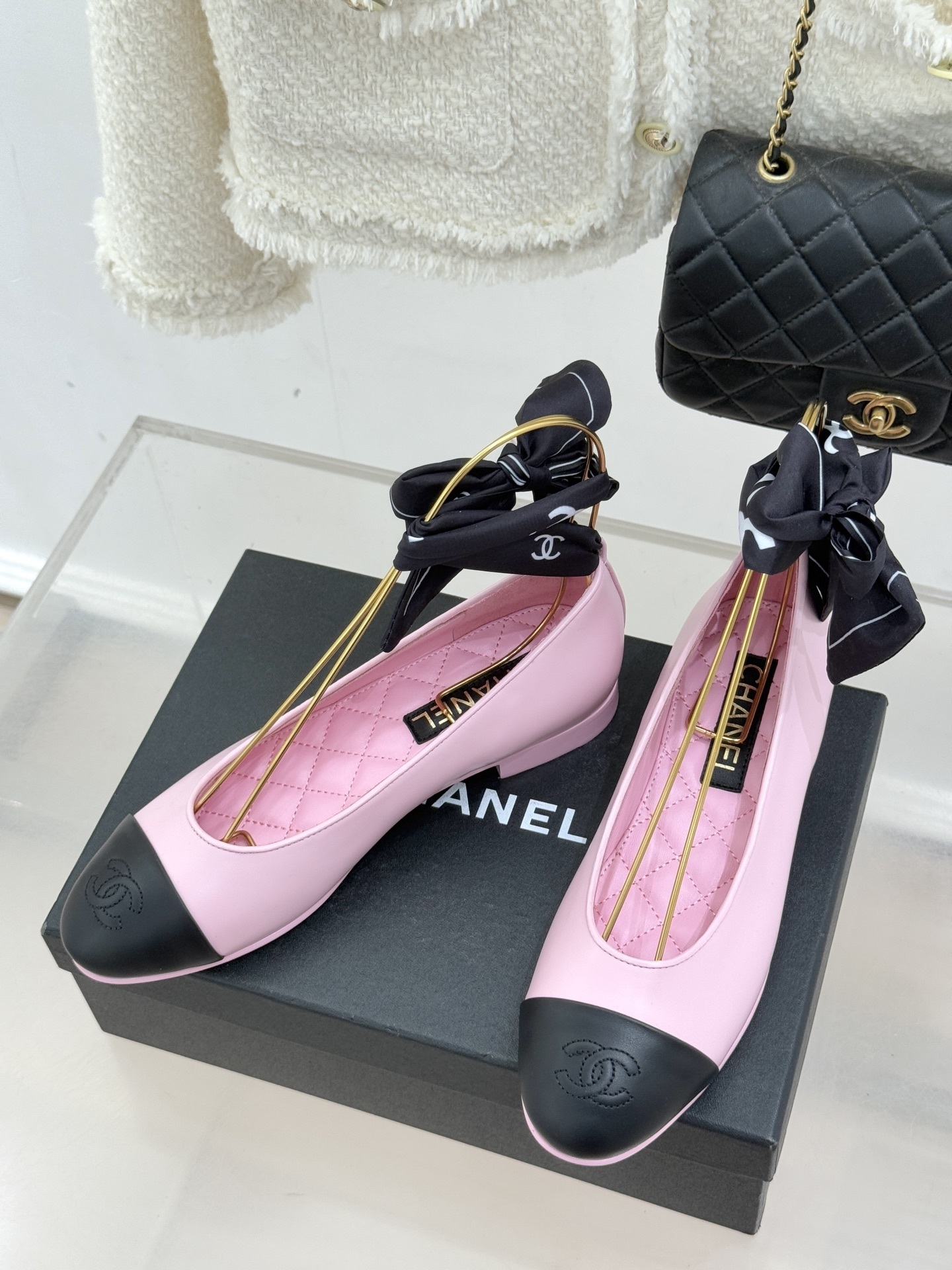 Luxury Chanel pink leather ballet flats with black toe caps and embossed logo on a branded box. - Hình 2