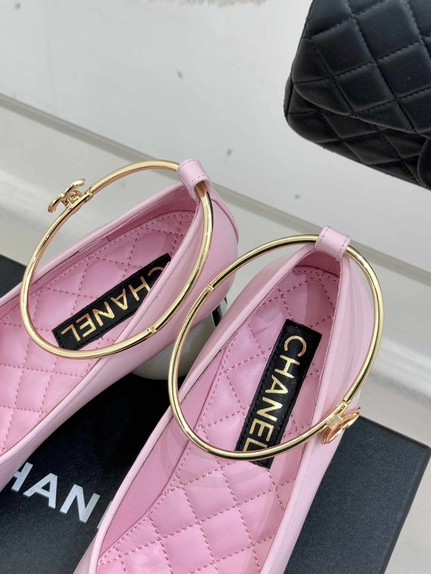 Chanel pink and black two-tone leather pumps with a large white pearl-shaped heel and gold-tone ankle ring displayed on a black box. - Hình 8