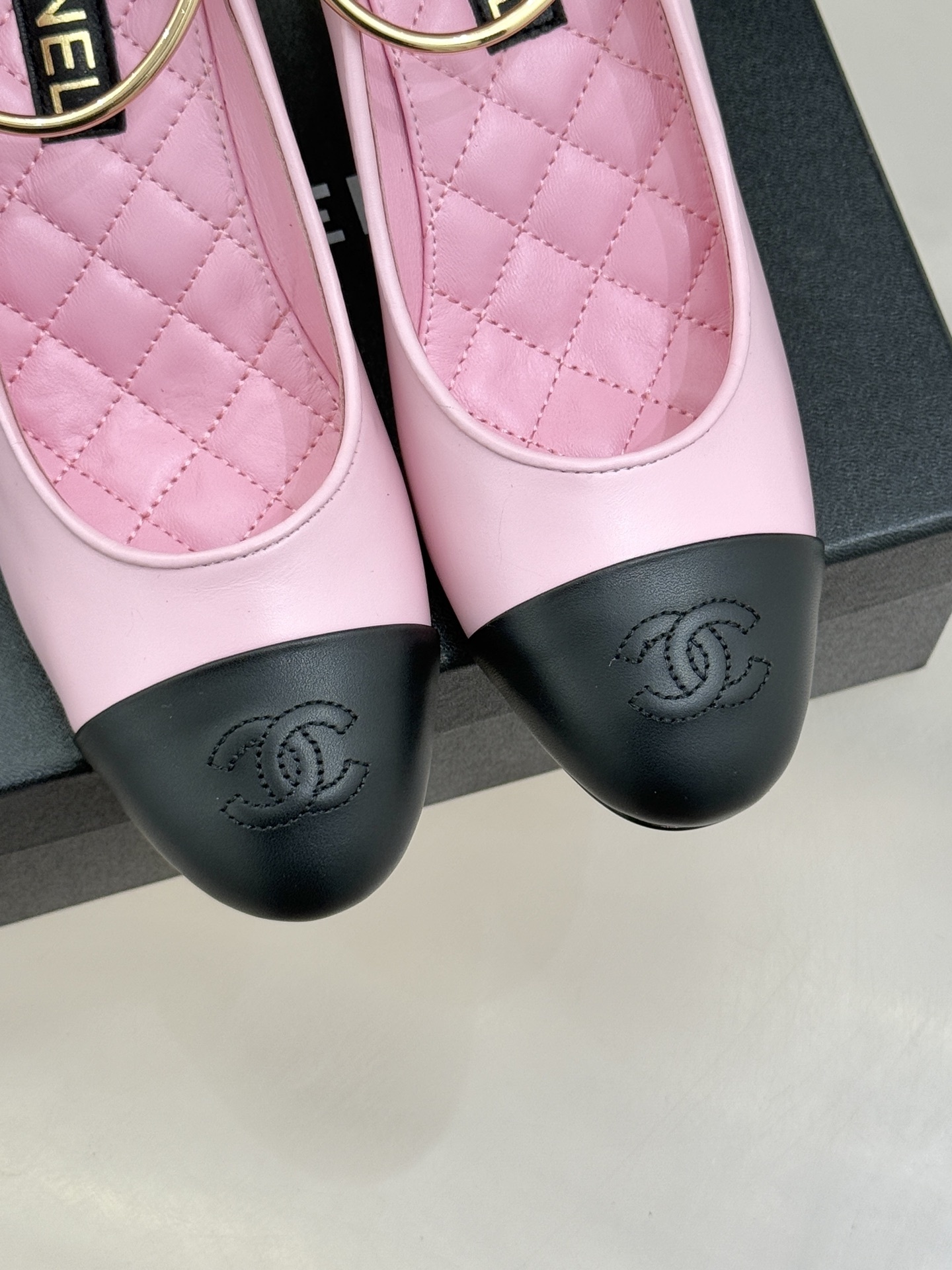Chanel pink and black two-tone leather pumps with a large white pearl-shaped heel and gold-tone ankle ring displayed on a black box. - Hình 7