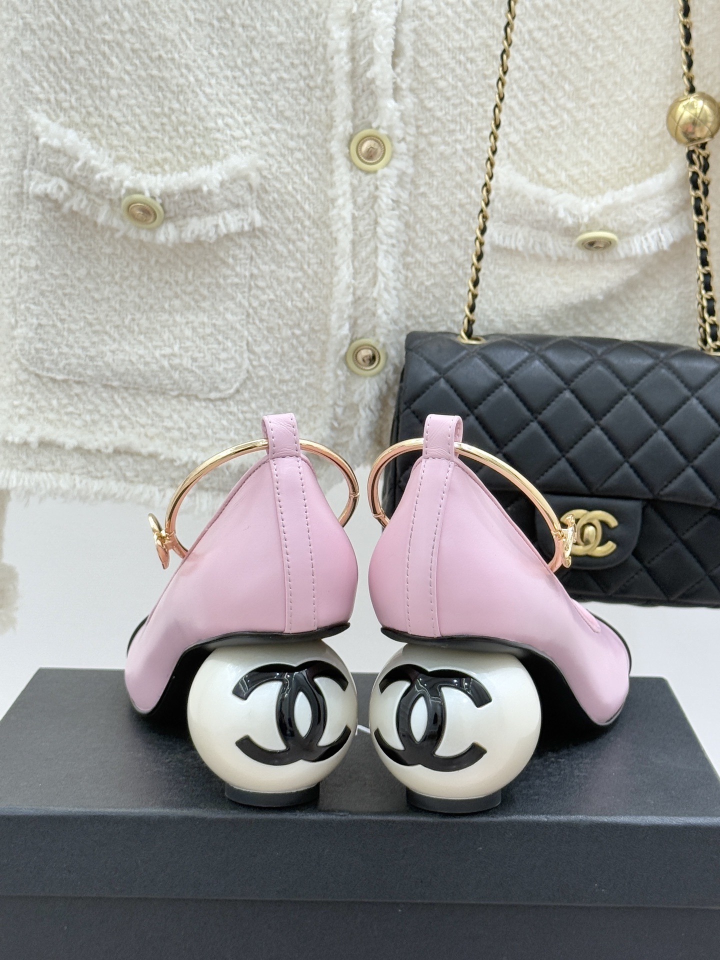 Chanel pink and black two-tone leather pumps with a large white pearl-shaped heel and gold-tone ankle ring displayed on a black box. - Hình 6