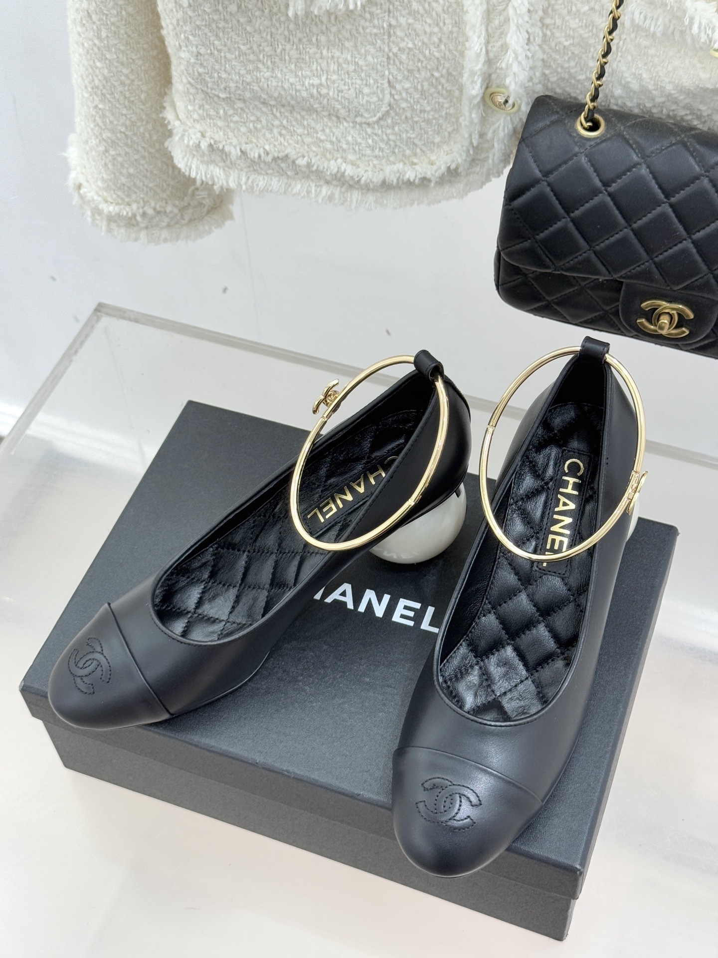 A pair of Chanel black leather pumps featuring unique white spherical pearl heels and gold-tone ankle straps with the CC logo. - Hình 2