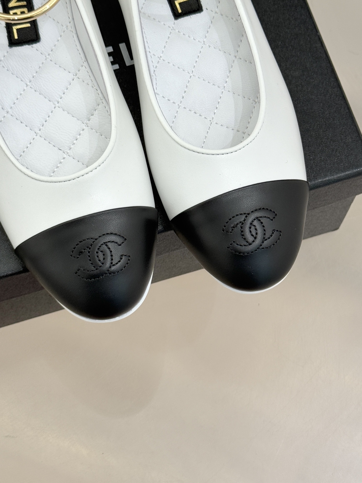 Pair of Chanel white leather ballet flats with black cap-toes and gold CC ankle rings displayed on a black Chanel box. - Hình 7