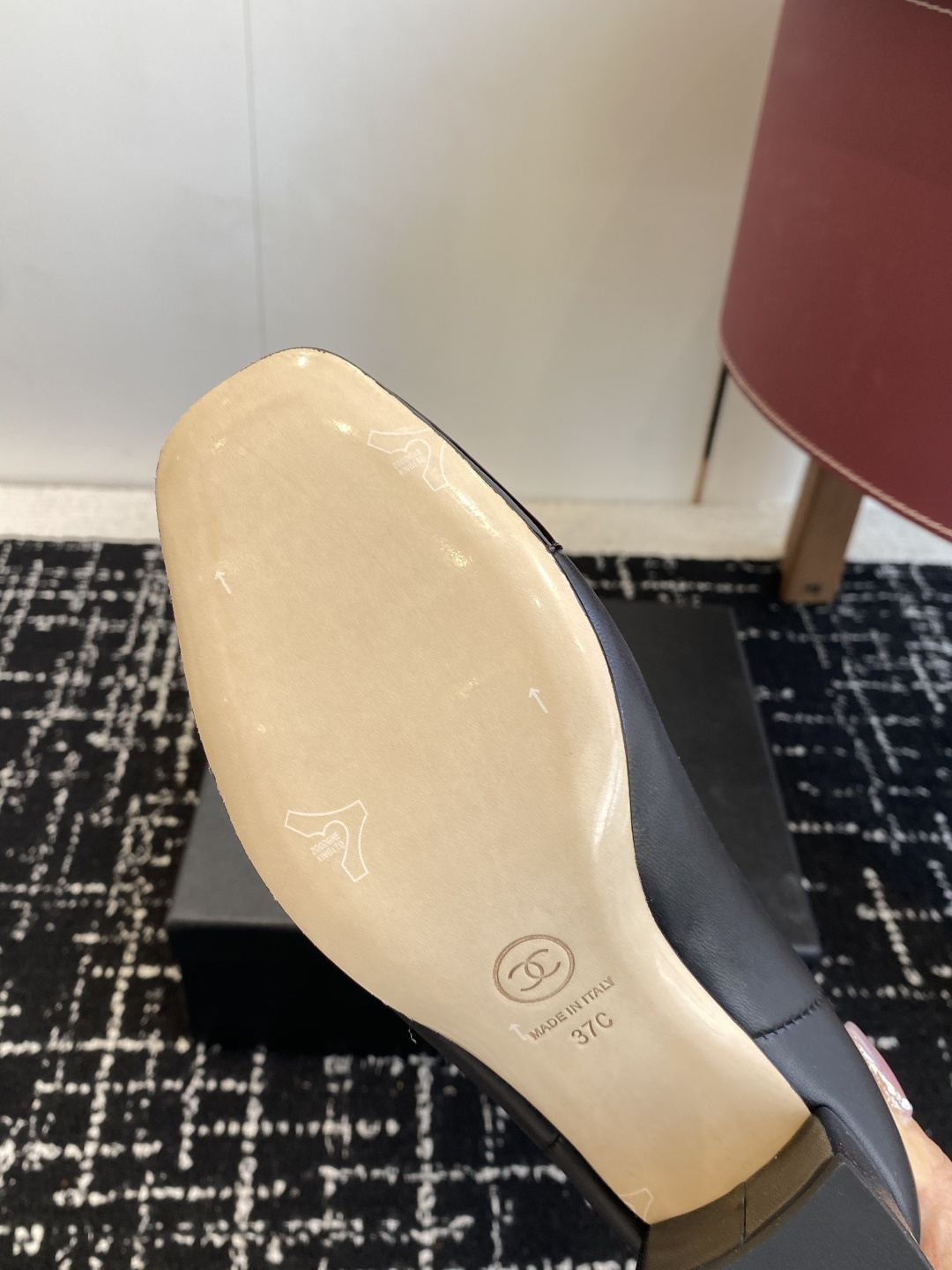 Pair of black Chanel leather ankle boots with patent leather cap-toe and CC logo on a black box. - Hình 9