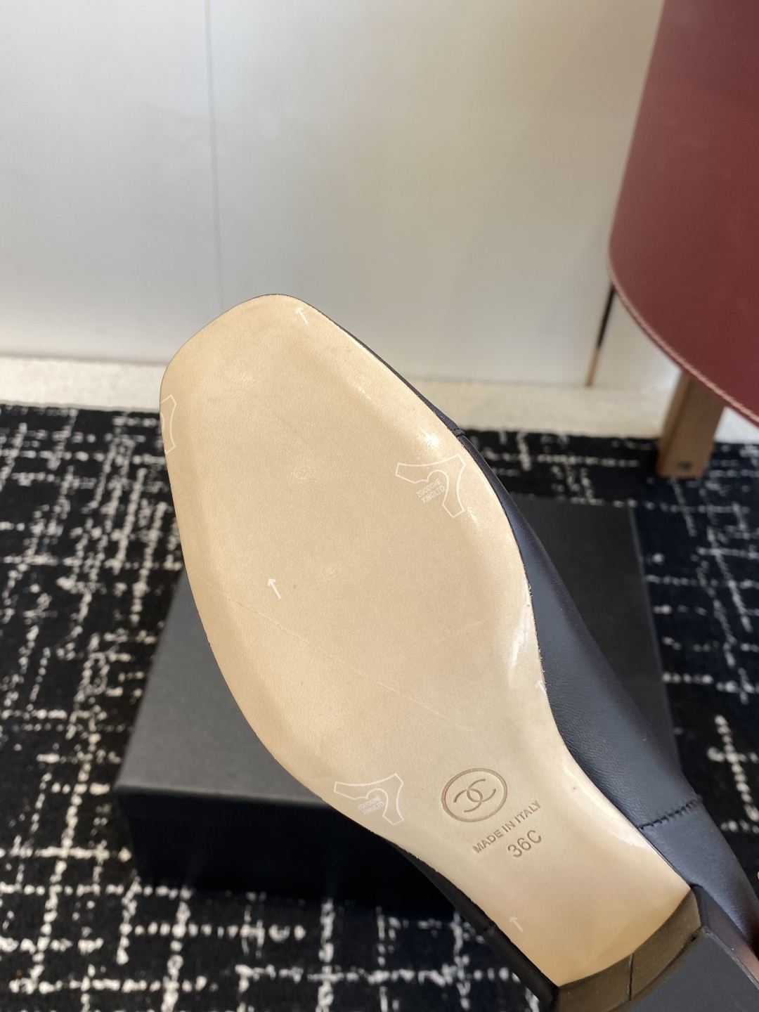 Chanel black leather Chelsea boots with signature CC logo on the toe cap and heel, displayed on a black box. - Hình 9