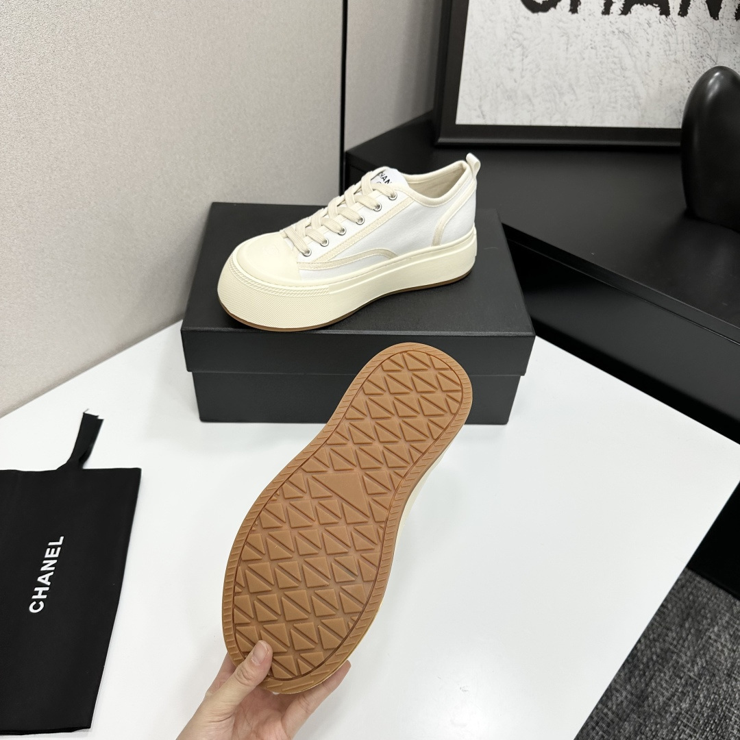 Side view of Chanel white canvas platform sneakers with chunky cream soles on a black box - Hình 4