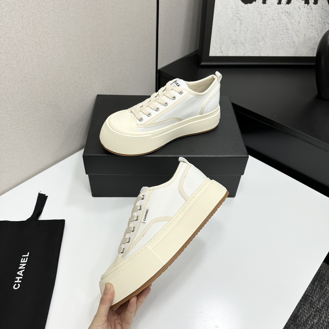 Side view of Chanel white canvas platform sneakers with chunky cream soles on a black box - Hình 3