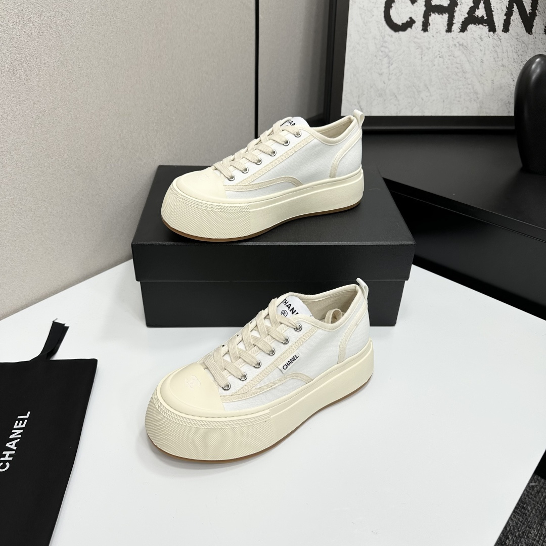 Side view of Chanel white canvas platform sneakers with chunky cream soles on a black box - Hình 2