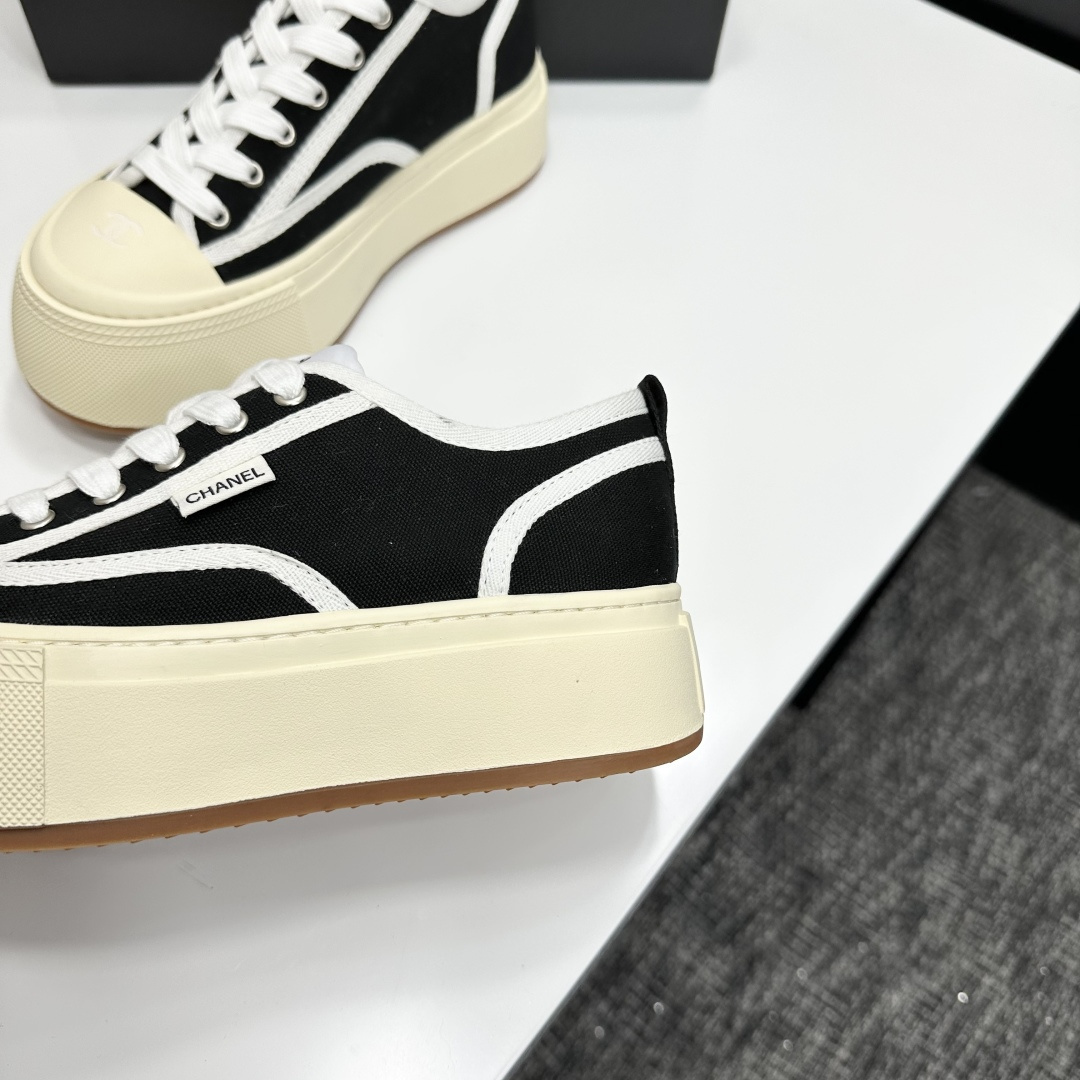 Chanel black canvas platform sneakers with white trim and thick cream soles on a black luxury box - Hình 8