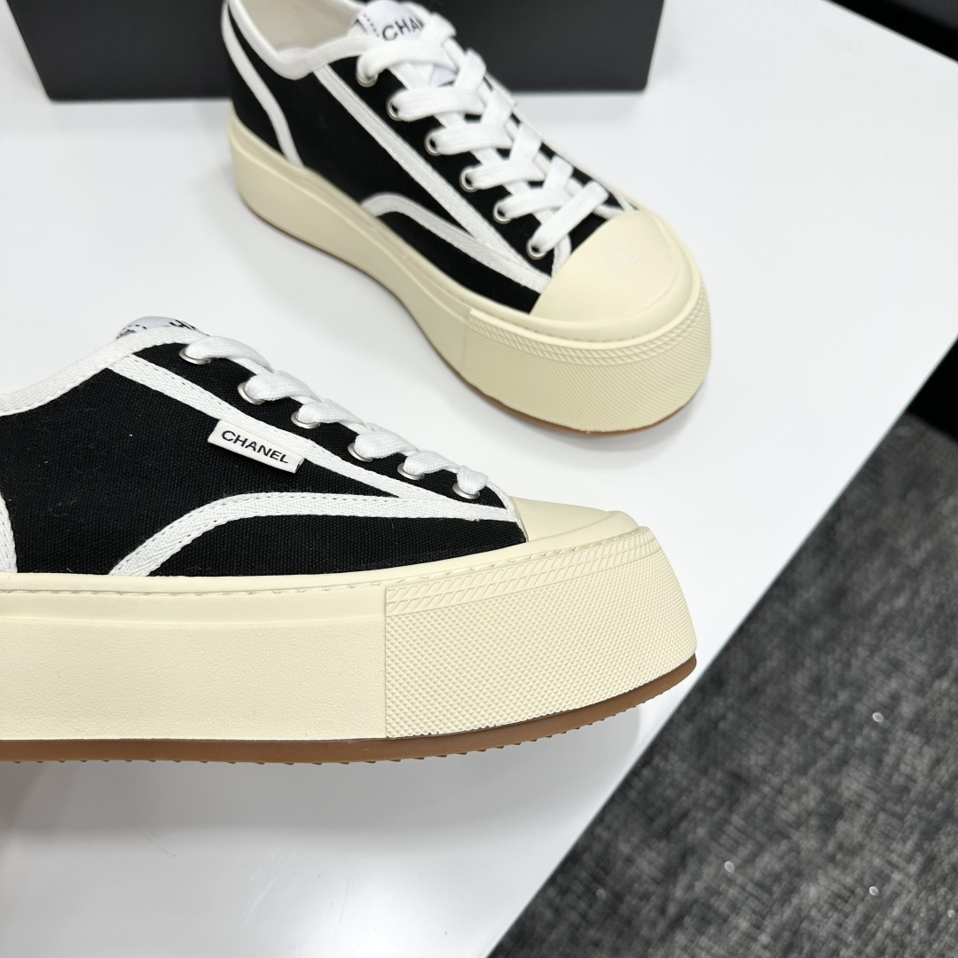 Chanel black canvas platform sneakers with white trim and thick cream soles on a black luxury box - Hình 2