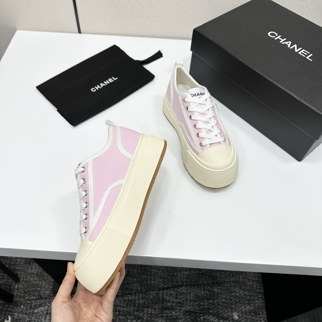 Chanel pink canvas sneakers with thick cream platform soles and white laces displayed on a black box. - Hình 9