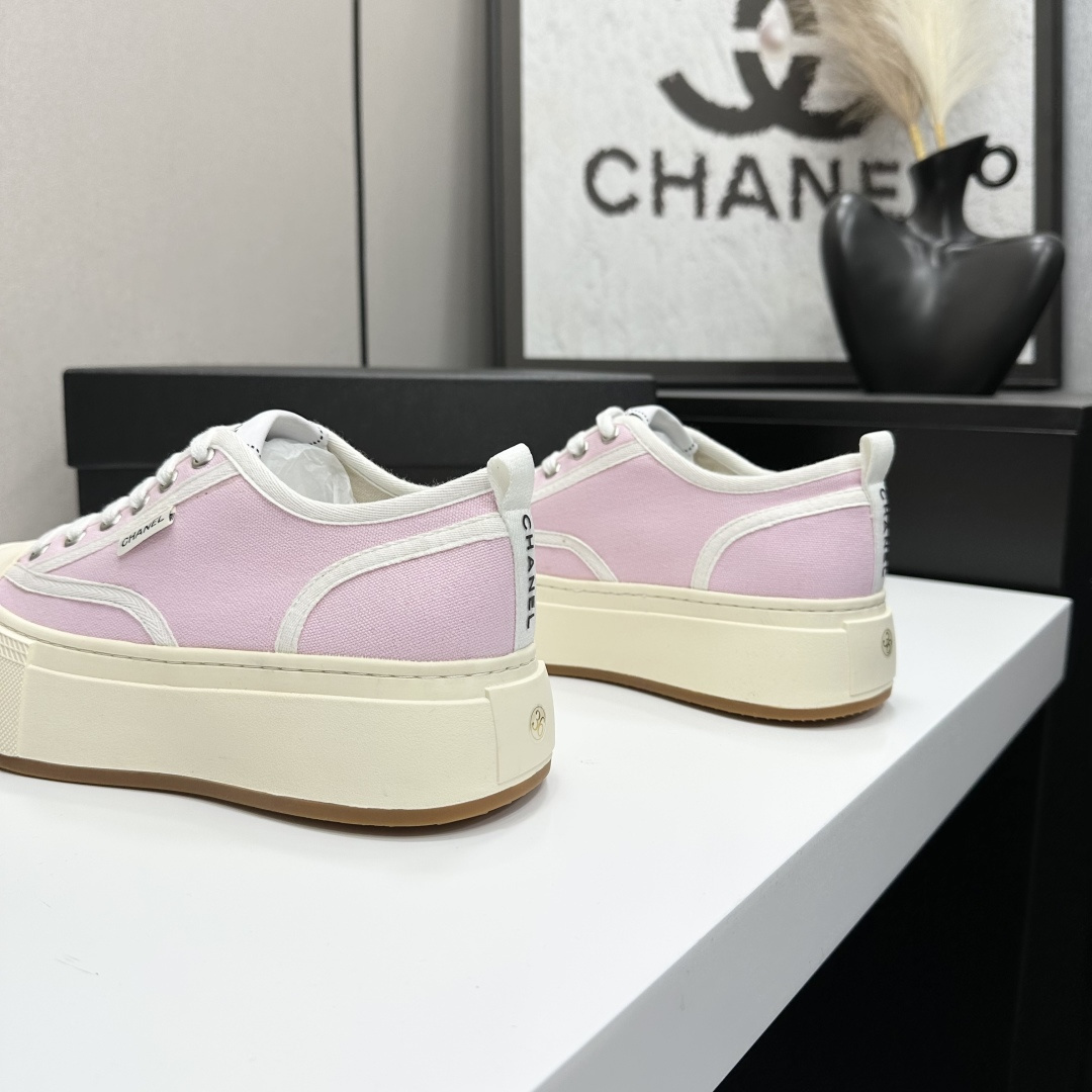 Chanel pink canvas sneakers with thick cream platform soles and white laces displayed on a black box. - Hình 7
