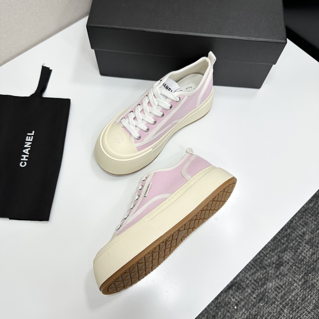 Chanel pink canvas sneakers with thick cream platform soles and white laces displayed on a black box. - Hình 6