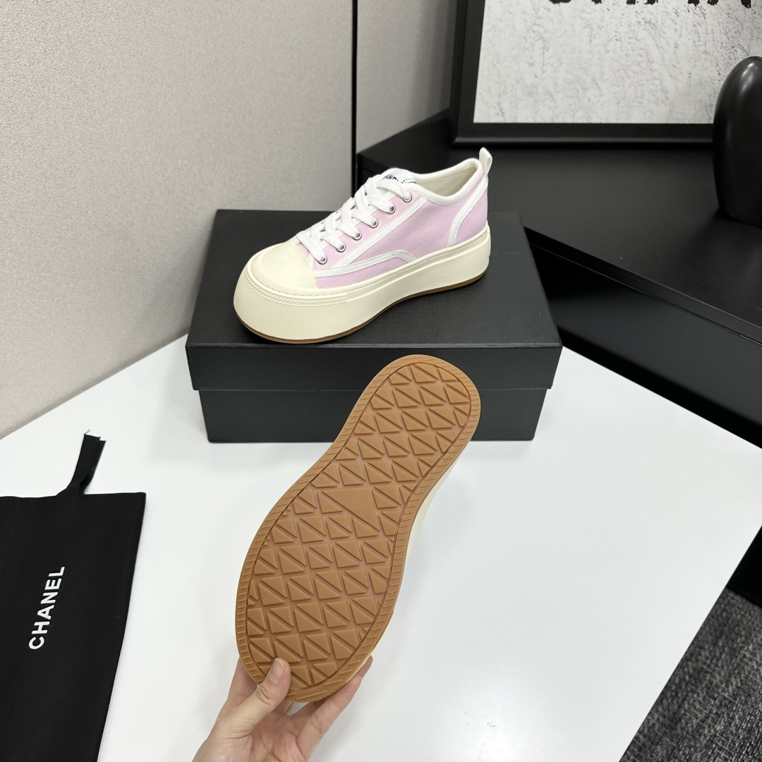 Chanel pink canvas sneakers with thick cream platform soles and white laces displayed on a black box. - Hình 4
