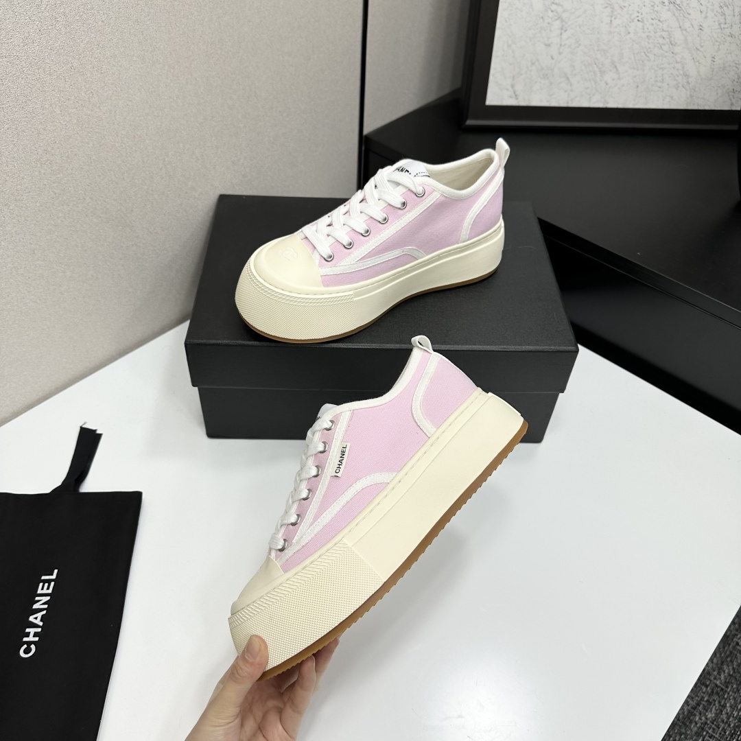 Chanel pink canvas sneakers with thick cream platform soles and white laces displayed on a black box. - Hình 3