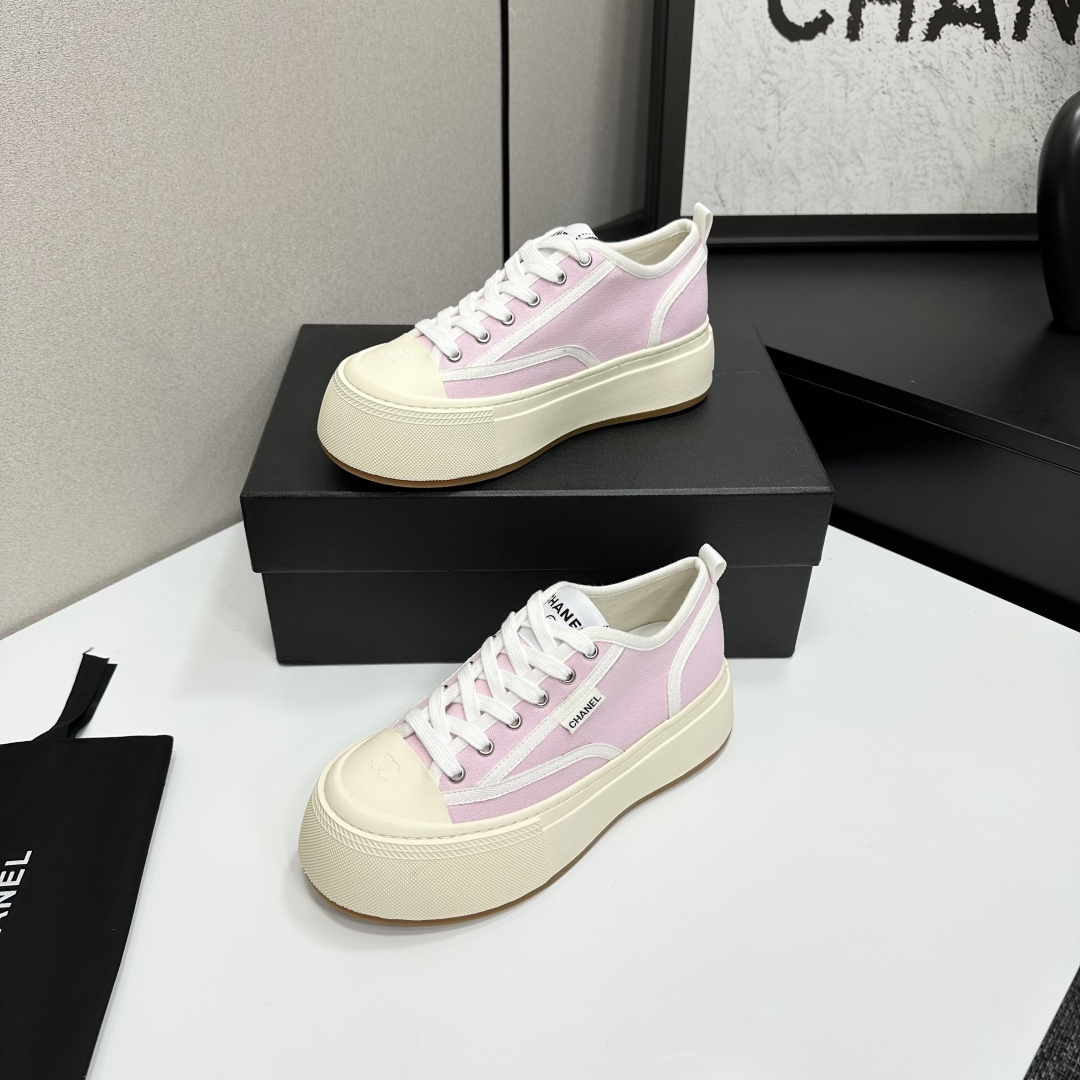 Chanel pink canvas sneakers with thick cream platform soles and white laces displayed on a black box. - Hình 2