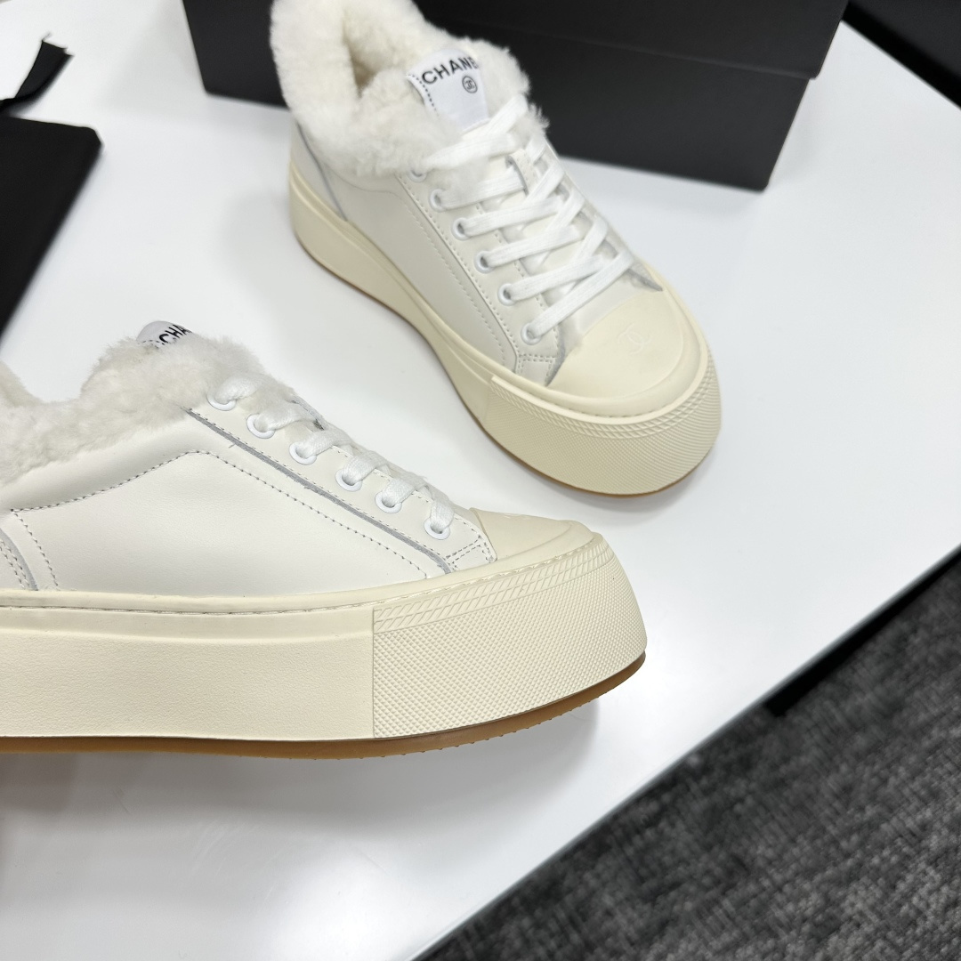 Pair of Chanel white leather platform sneakers with white shearling lining displayed on a black box - Hình 9