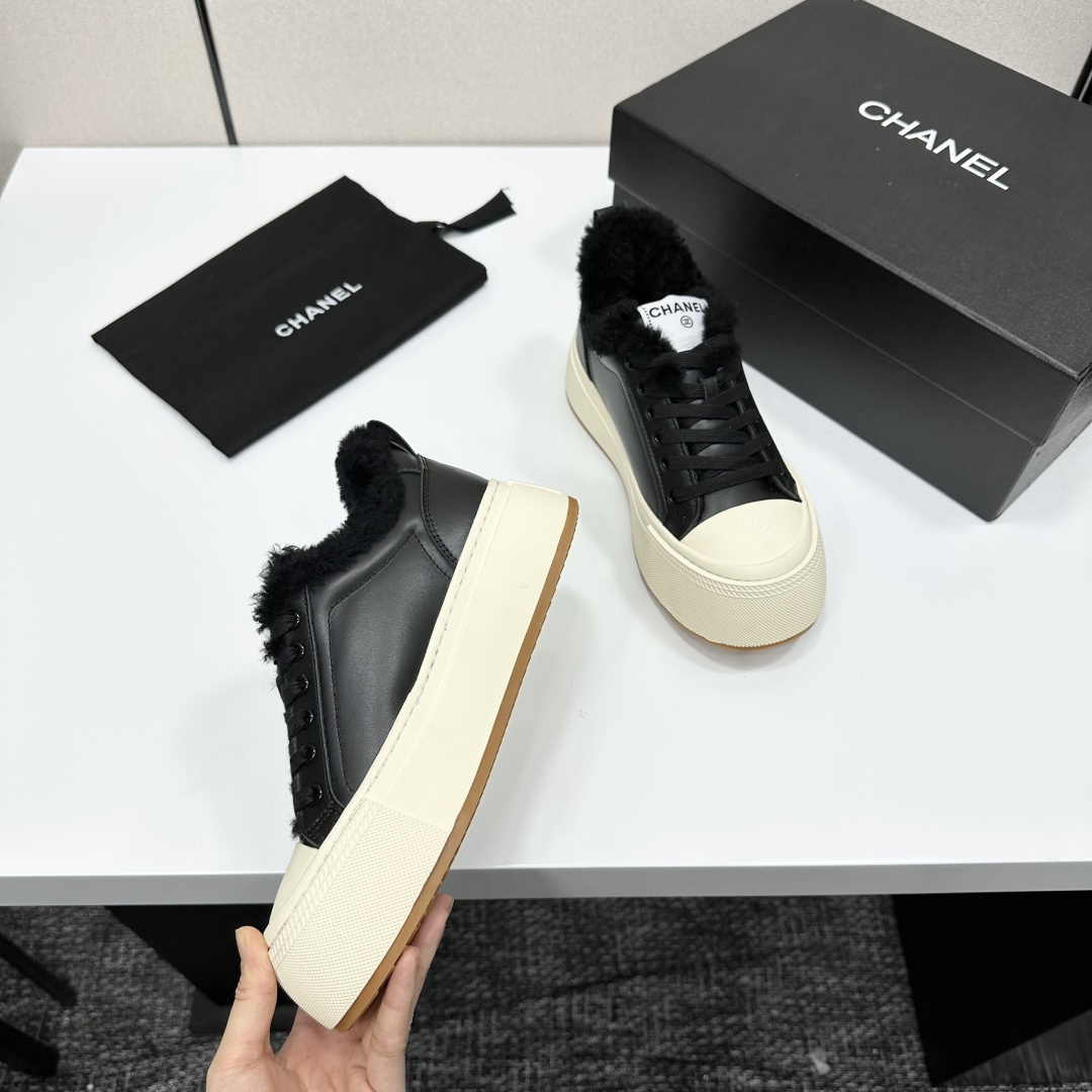 Luxury black leather Chanel sneakers with white platform soles and black fur lining displayed on a black box - Hình 9