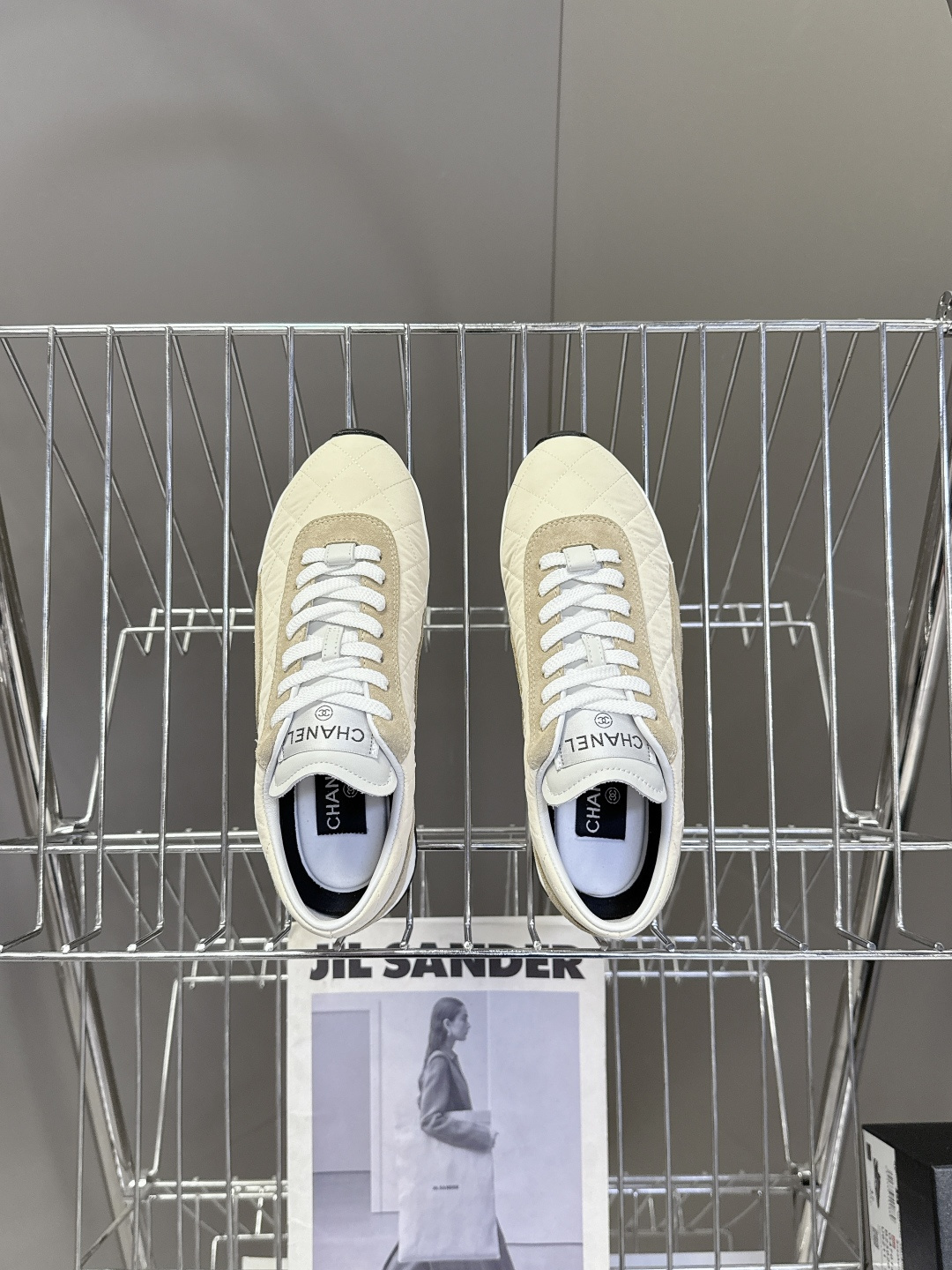 A pair of luxury Chanel quilted sneakers in beige and tan suede featuring the CC logo, placed next to a blue Chanel box. - Hình 6