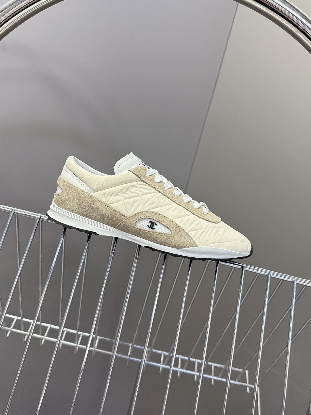 A pair of luxury Chanel quilted sneakers in beige and tan suede featuring the CC logo, placed next to a blue Chanel box. - Hình 5