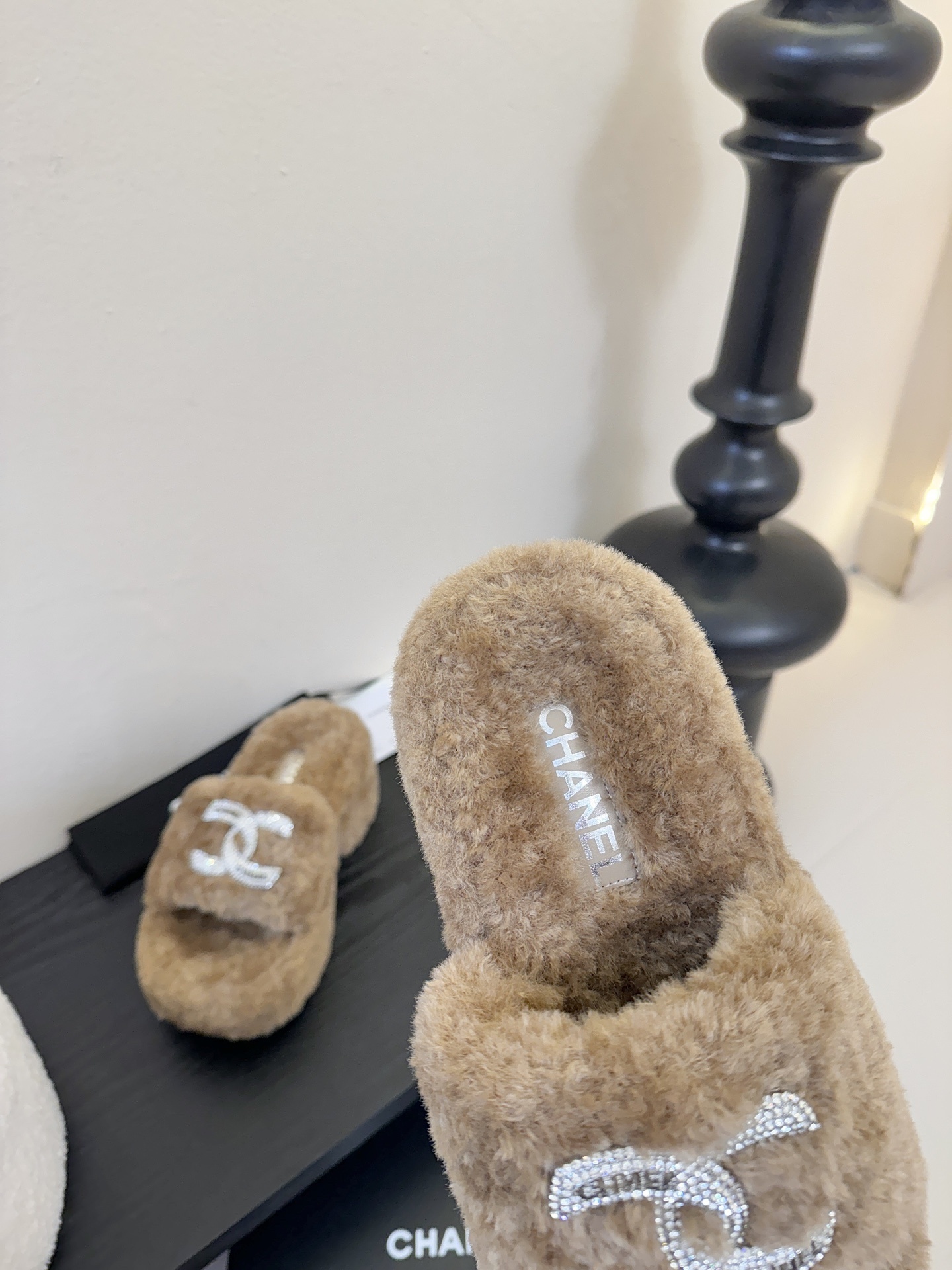 Pair of brown Chanel fluffy shearling platform slides with crystal CC logo on a black display table - Hình 8