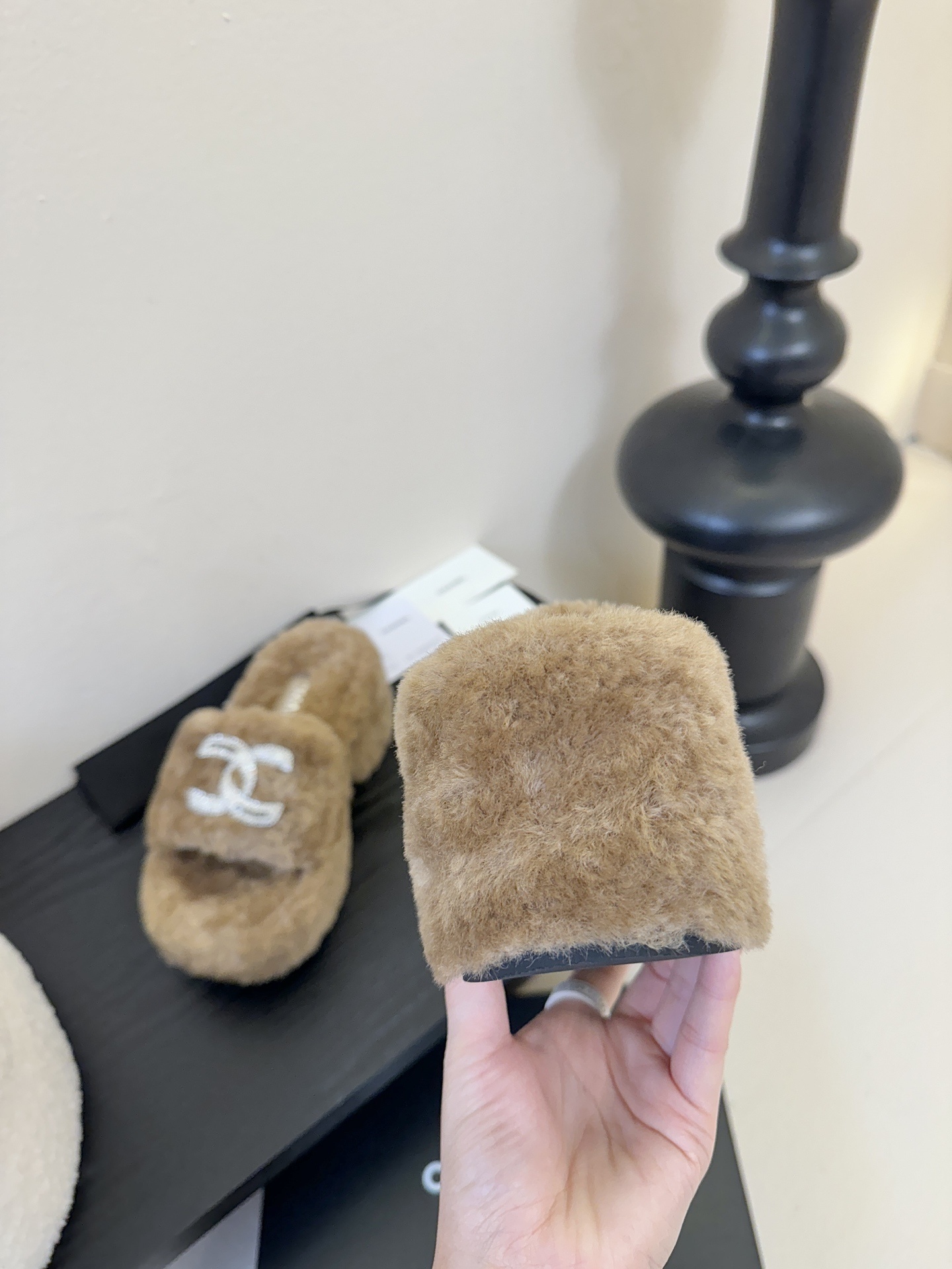 Pair of brown Chanel fluffy shearling platform slides with crystal CC logo on a black display table - Hình 7