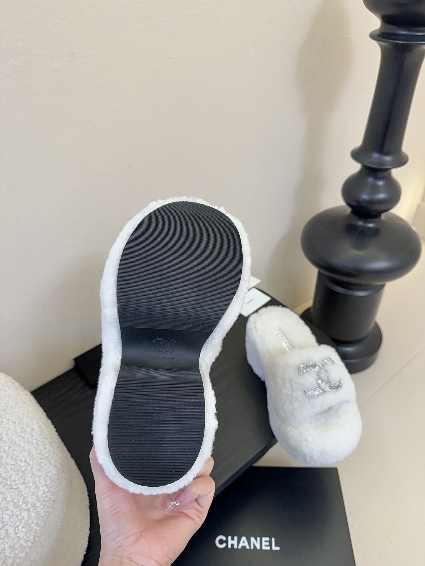 Pair of white fluffy Chanel platform slide sandals with rhinestone CC logo displayed on a black surface - Hình 9