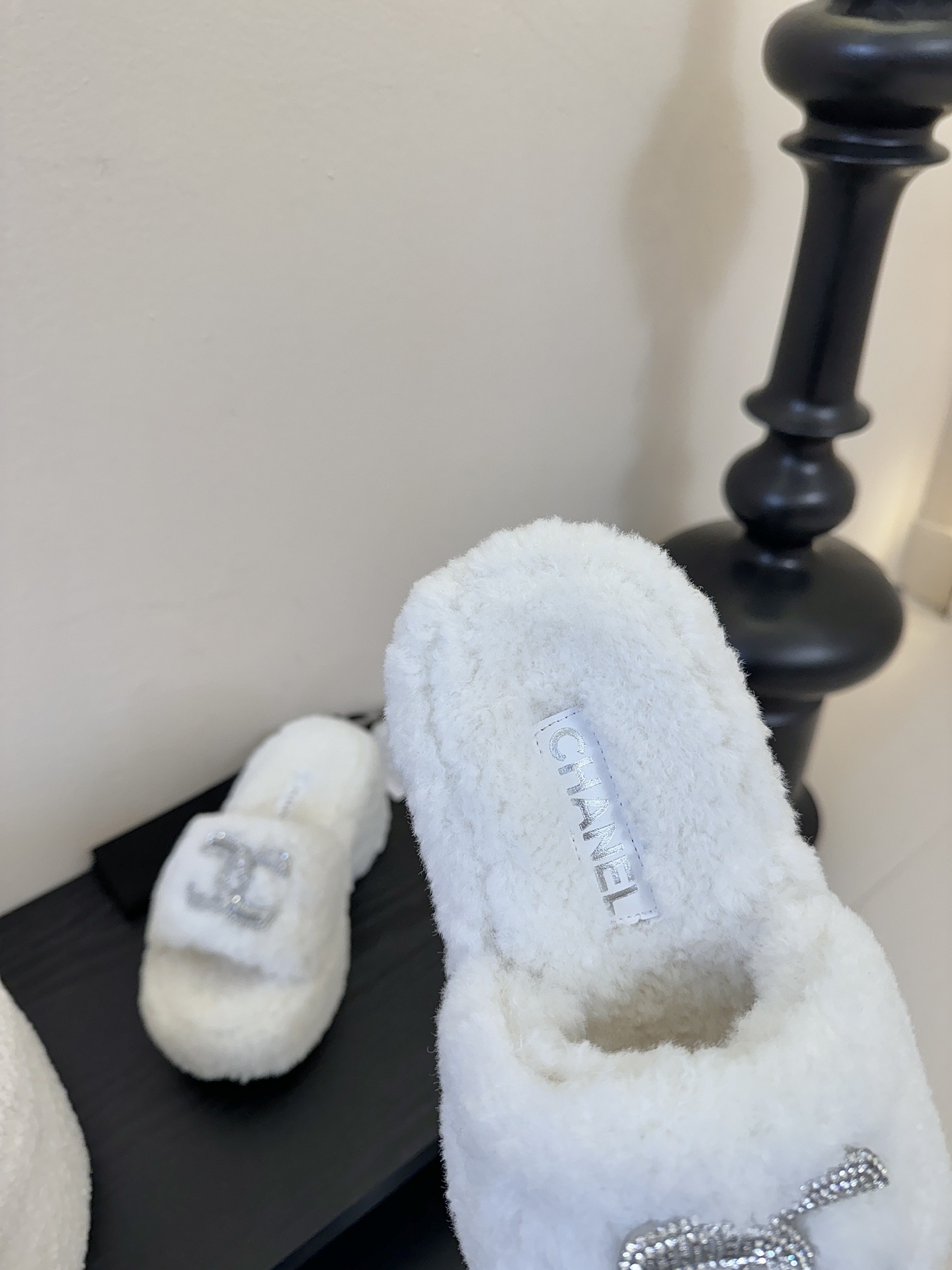 Pair of white fluffy Chanel platform slide sandals with rhinestone CC logo displayed on a black surface - Hình 8