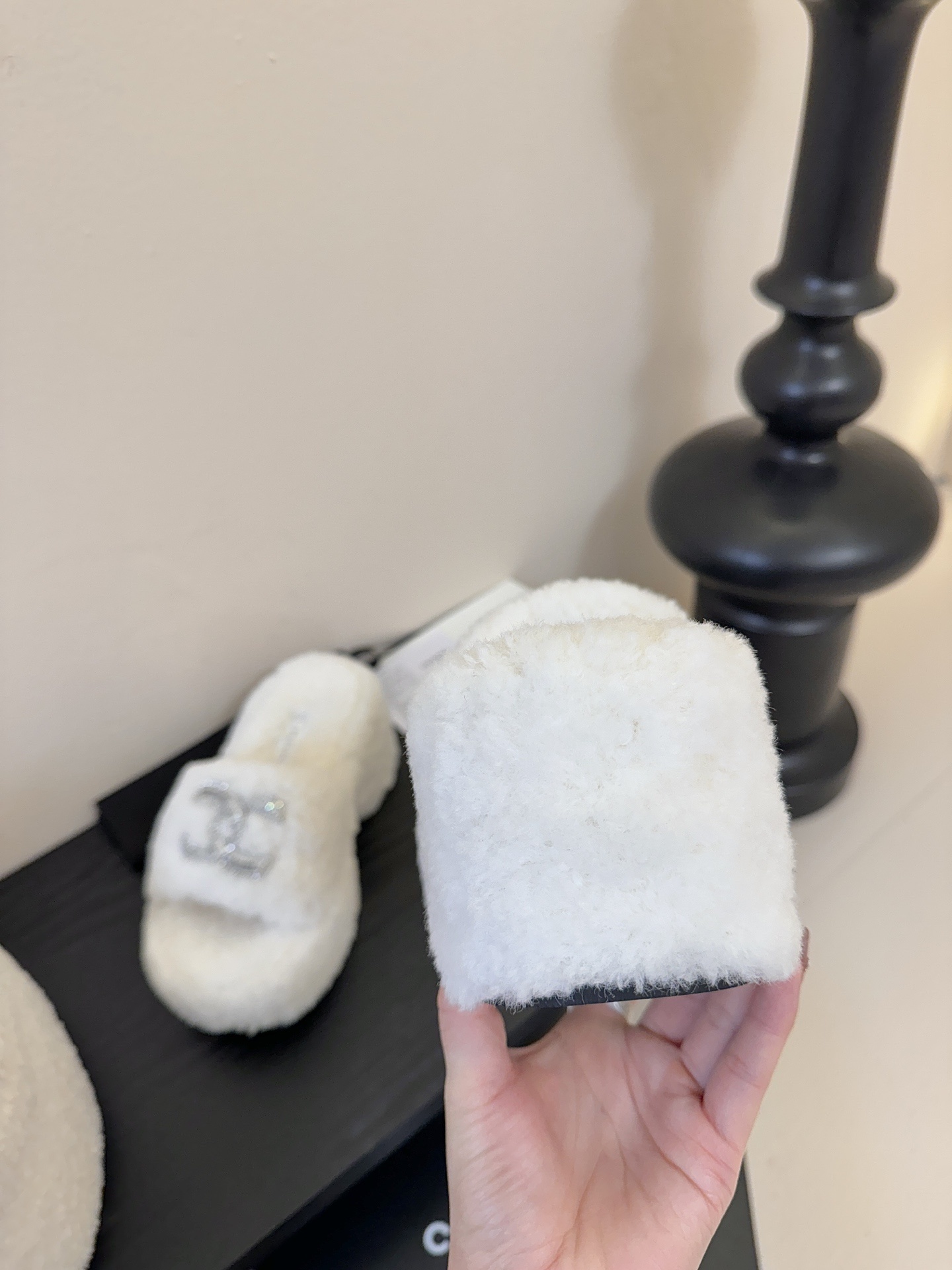 Pair of white fluffy Chanel platform slide sandals with rhinestone CC logo displayed on a black surface - Hình 7