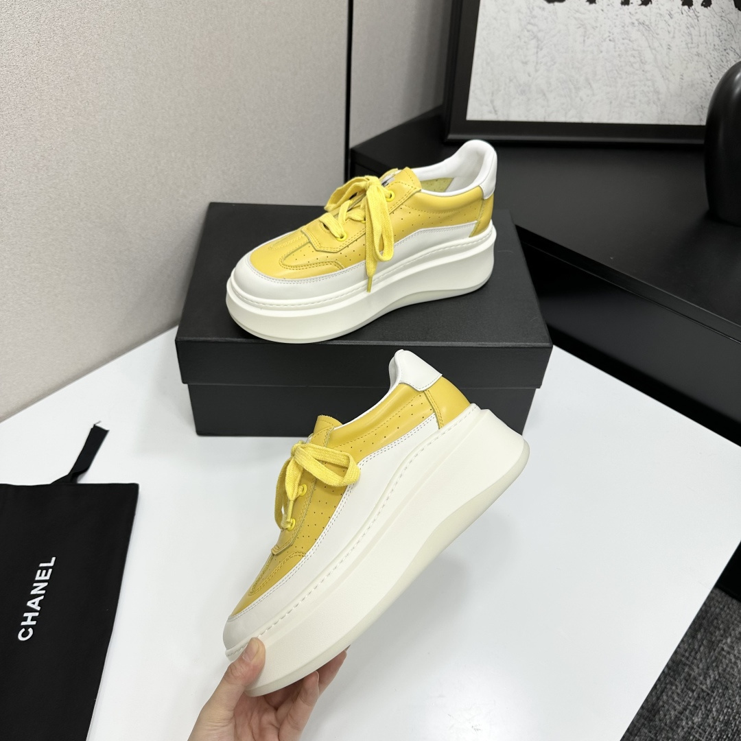 A pair of luxury Chanel yellow and white platform sneakers displayed on a black box with a branded dust bag. - Hình 3