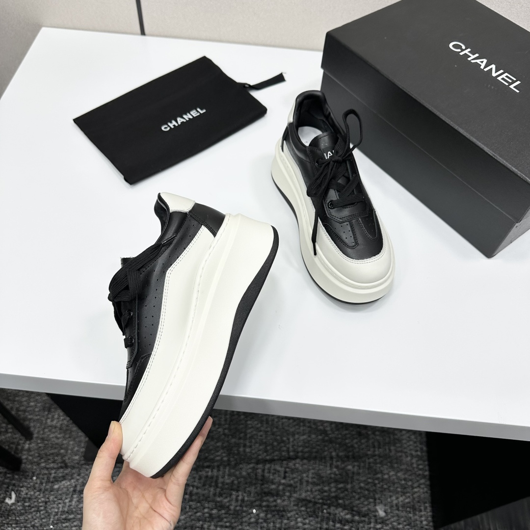Pair of luxury Chanel black and white leather platform sneakers with a thick white chunky sole displayed on a black box. - Hình 9