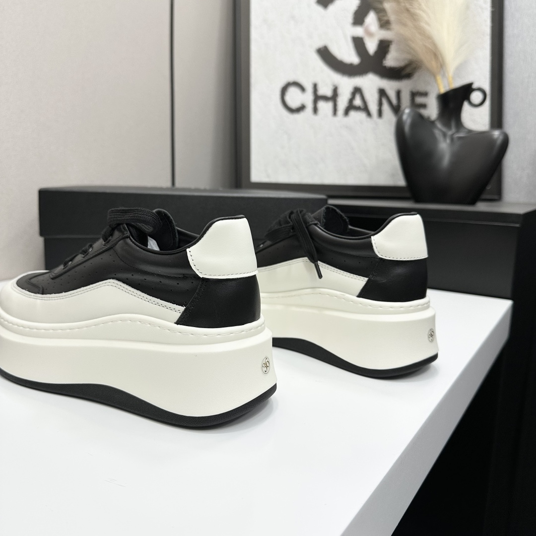 Pair of luxury Chanel black and white leather platform sneakers with a thick white chunky sole displayed on a black box. - Hình 6