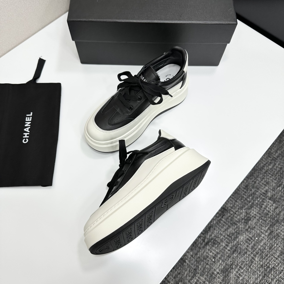 Pair of luxury Chanel black and white leather platform sneakers with a thick white chunky sole displayed on a black box. - Hình 5