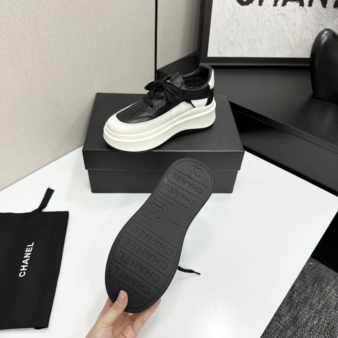 Pair of luxury Chanel black and white leather platform sneakers with a thick white chunky sole displayed on a black box. - Hình 4