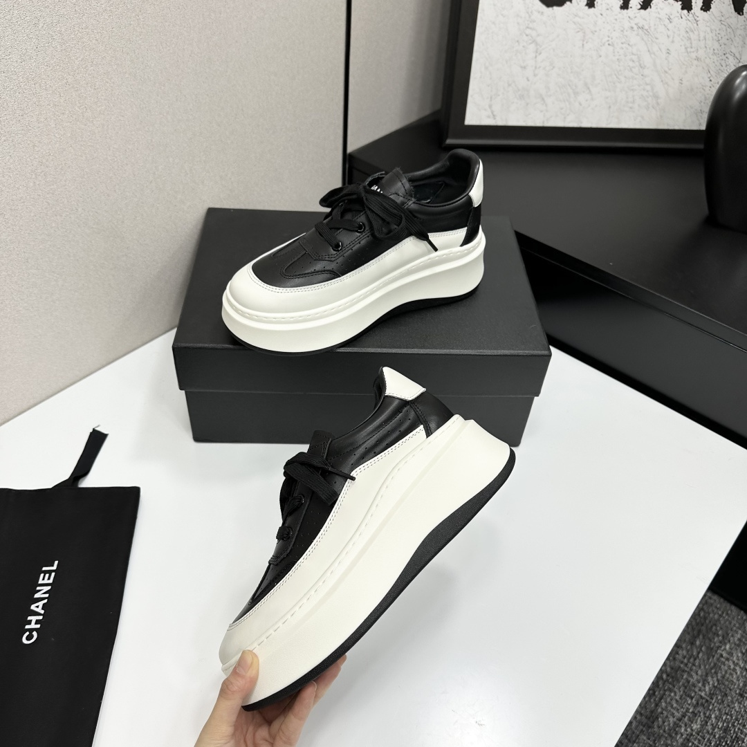 Pair of luxury Chanel black and white leather platform sneakers with a thick white chunky sole displayed on a black box. - Hình 3