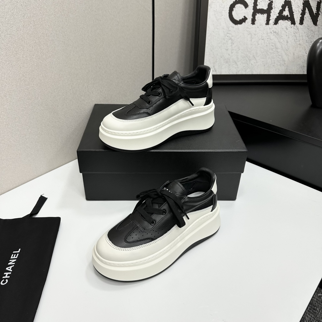 Pair of luxury Chanel black and white leather platform sneakers with a thick white chunky sole displayed on a black box. - Hình 2
