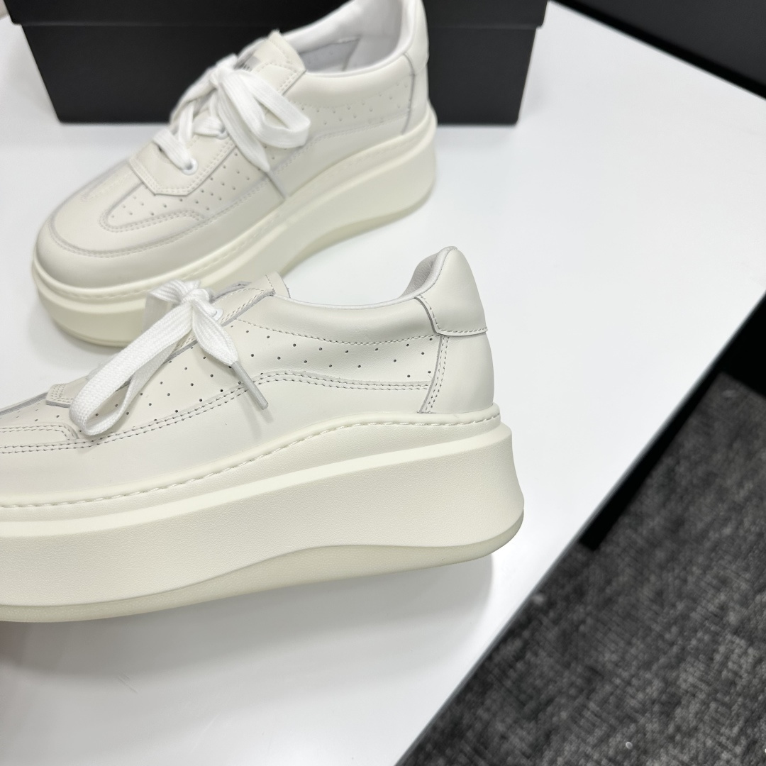 Pair of luxury Chanel white leather platform sneakers with chunky soles and lace-up design on a black display box. - Hình 9