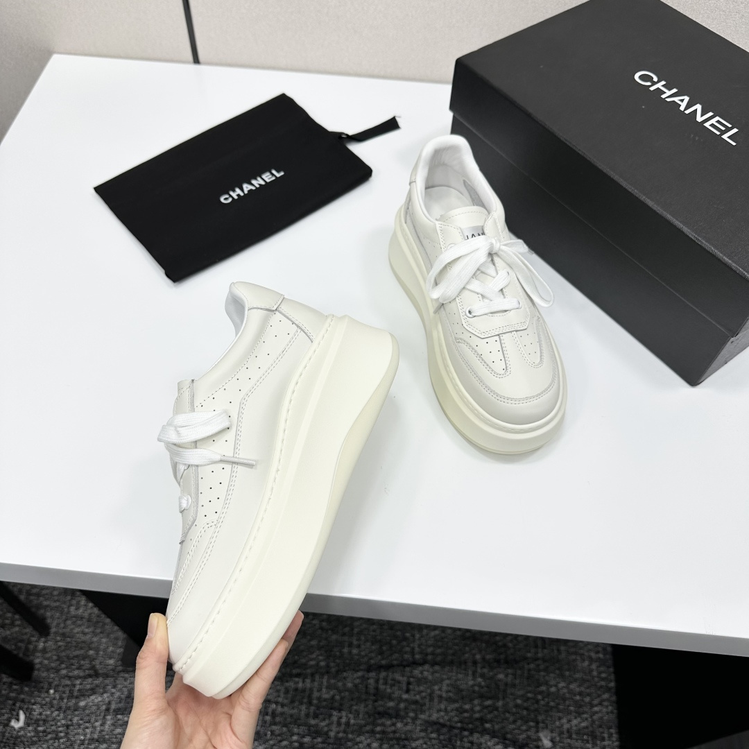 Pair of luxury Chanel white leather platform sneakers with chunky soles and lace-up design on a black display box. - Hình 8