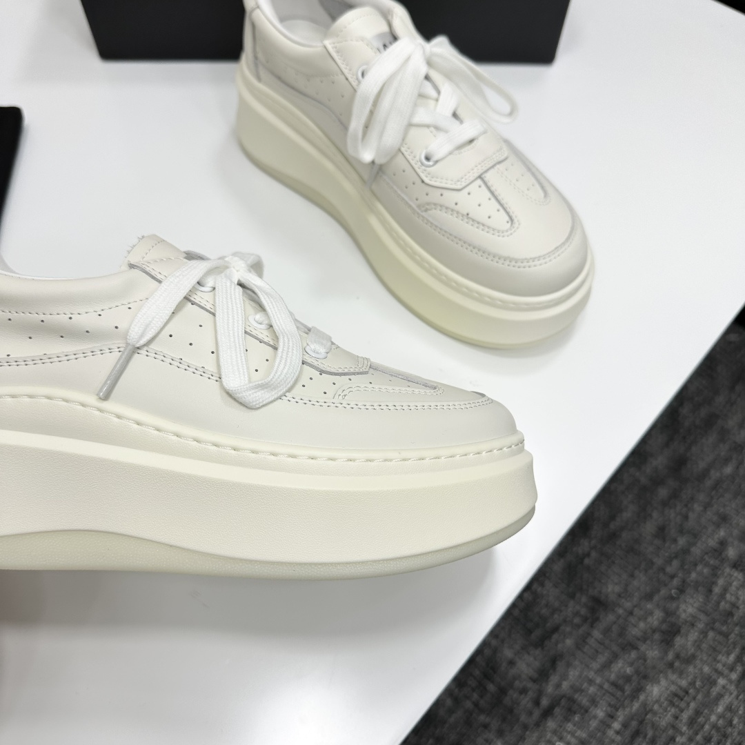 Pair of luxury Chanel white leather platform sneakers with chunky soles and lace-up design on a black display box. - Hình 7