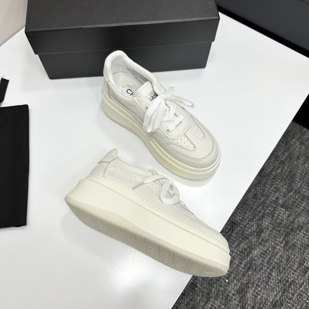 Pair of luxury Chanel white leather platform sneakers with chunky soles and lace-up design on a black display box. - Hình 6
