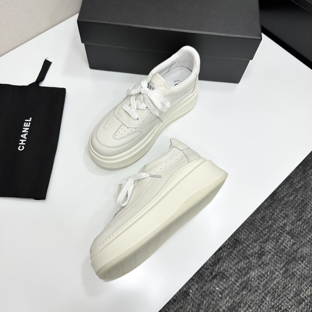 Pair of luxury Chanel white leather platform sneakers with chunky soles and lace-up design on a black display box. - Hình 4