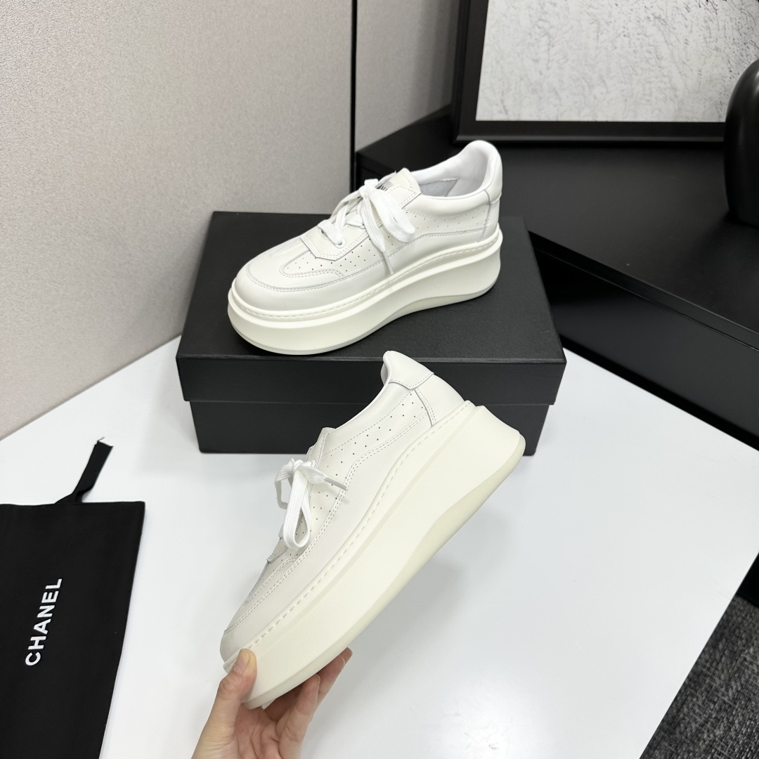 Pair of luxury Chanel white leather platform sneakers with chunky soles and lace-up design on a black display box. - Hình 3