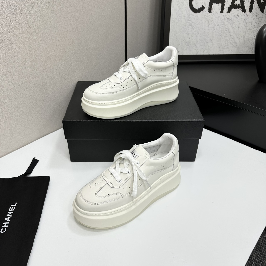 Pair of luxury Chanel white leather platform sneakers with chunky soles and lace-up design on a black display box. - Hình 2